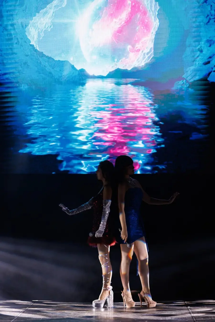 青とピンクの幻想的なステージでパフォーマンスする女性たち