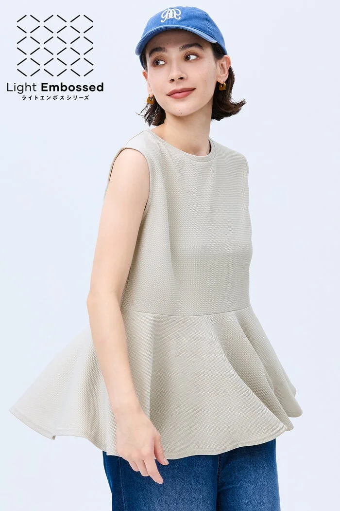 ベージュのペプラムトップスとジーンズを着用した若い女性