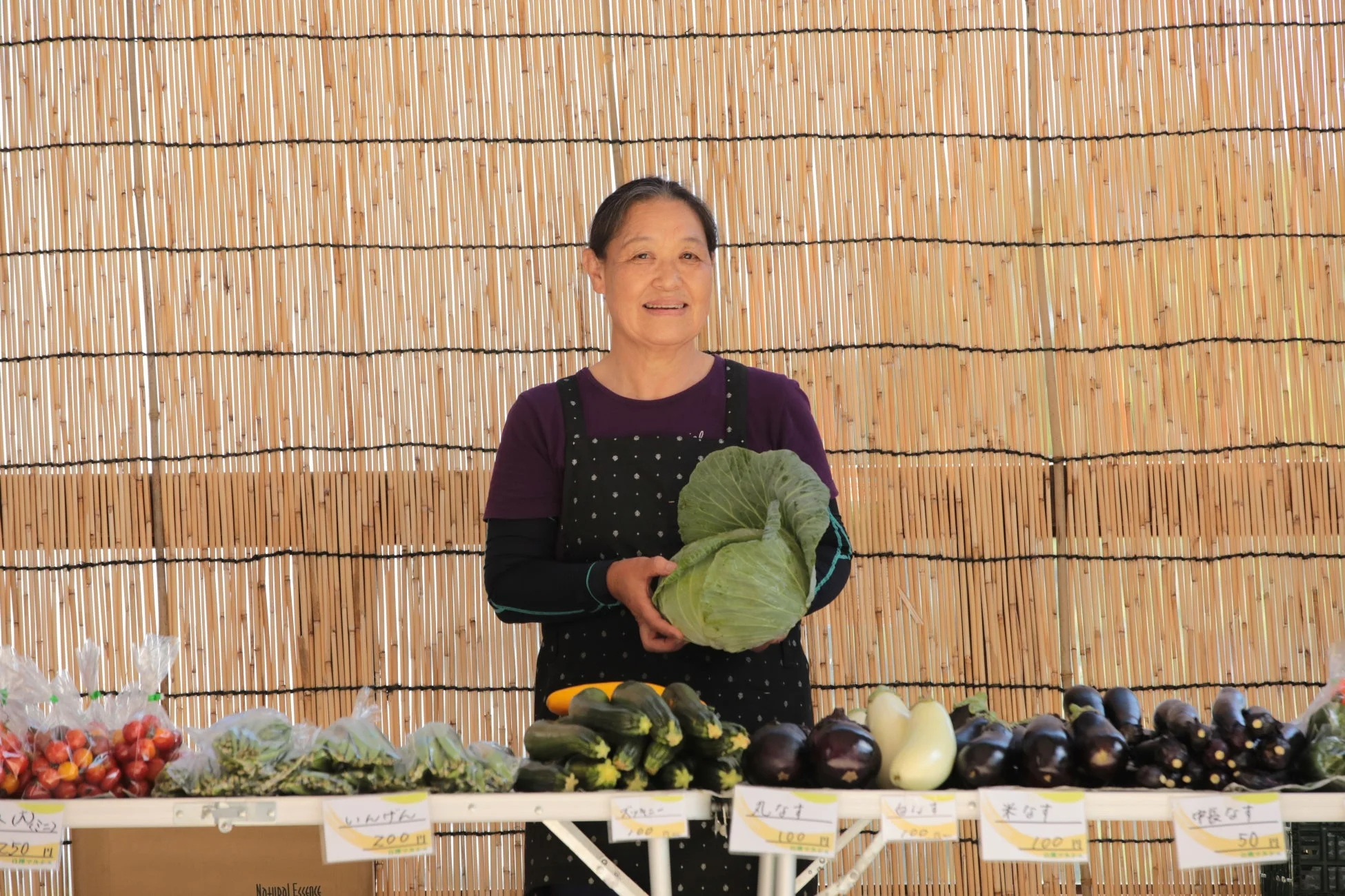 野菜を販売する女性と並べられた野菜