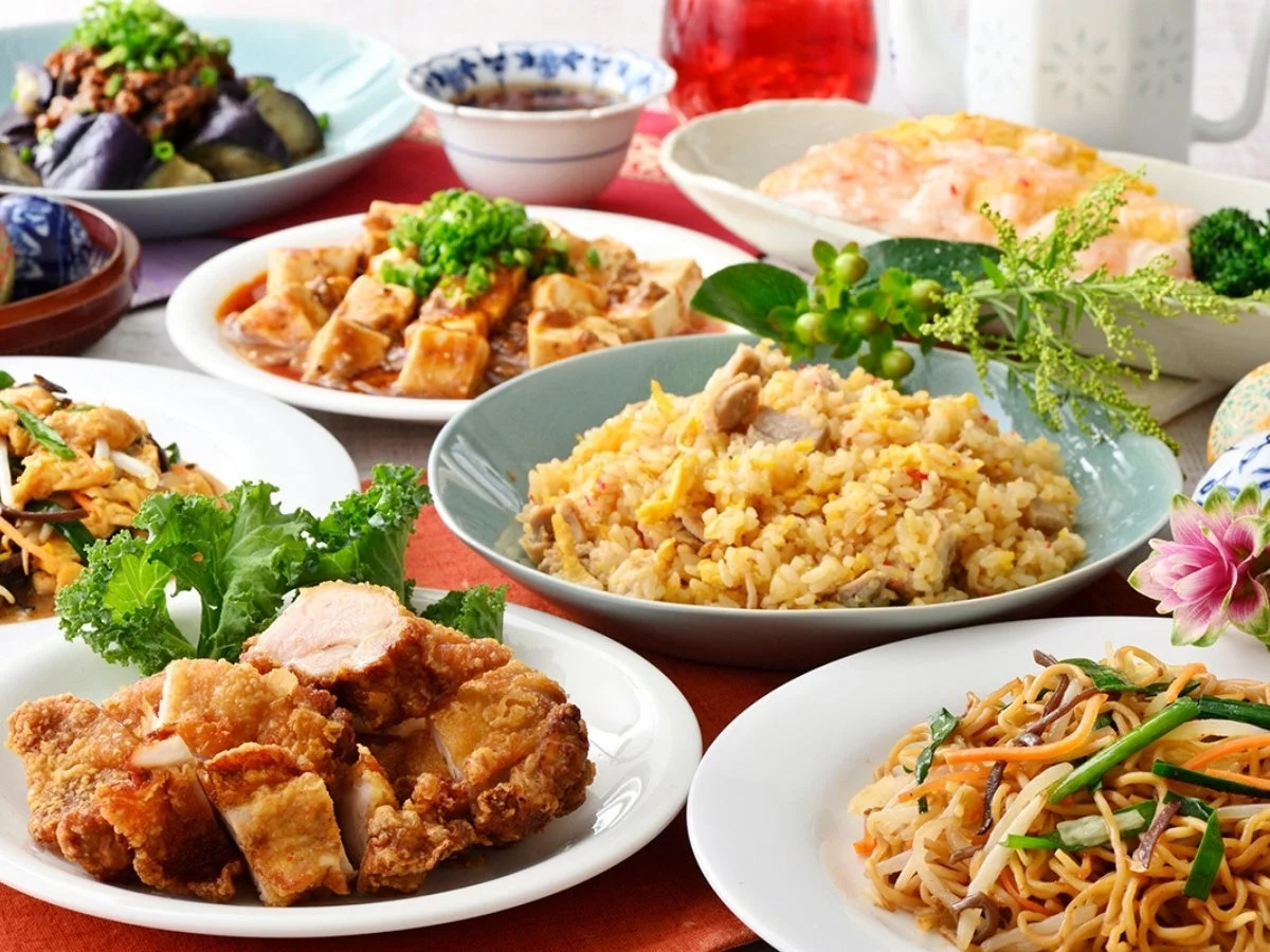 テーブルいっぱいに豪華な中華料理が並べられた食卓の様子。フライドチキン、チャーハン、麻婆豆腐、焼きそばなど、彩り豊かで食欲をそそる様々な料理が一度に楽しめる光景です。