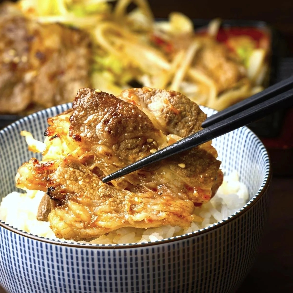 ご飯の上に香ばしく焼かれた肉と野菜が盛り付けられた丼物