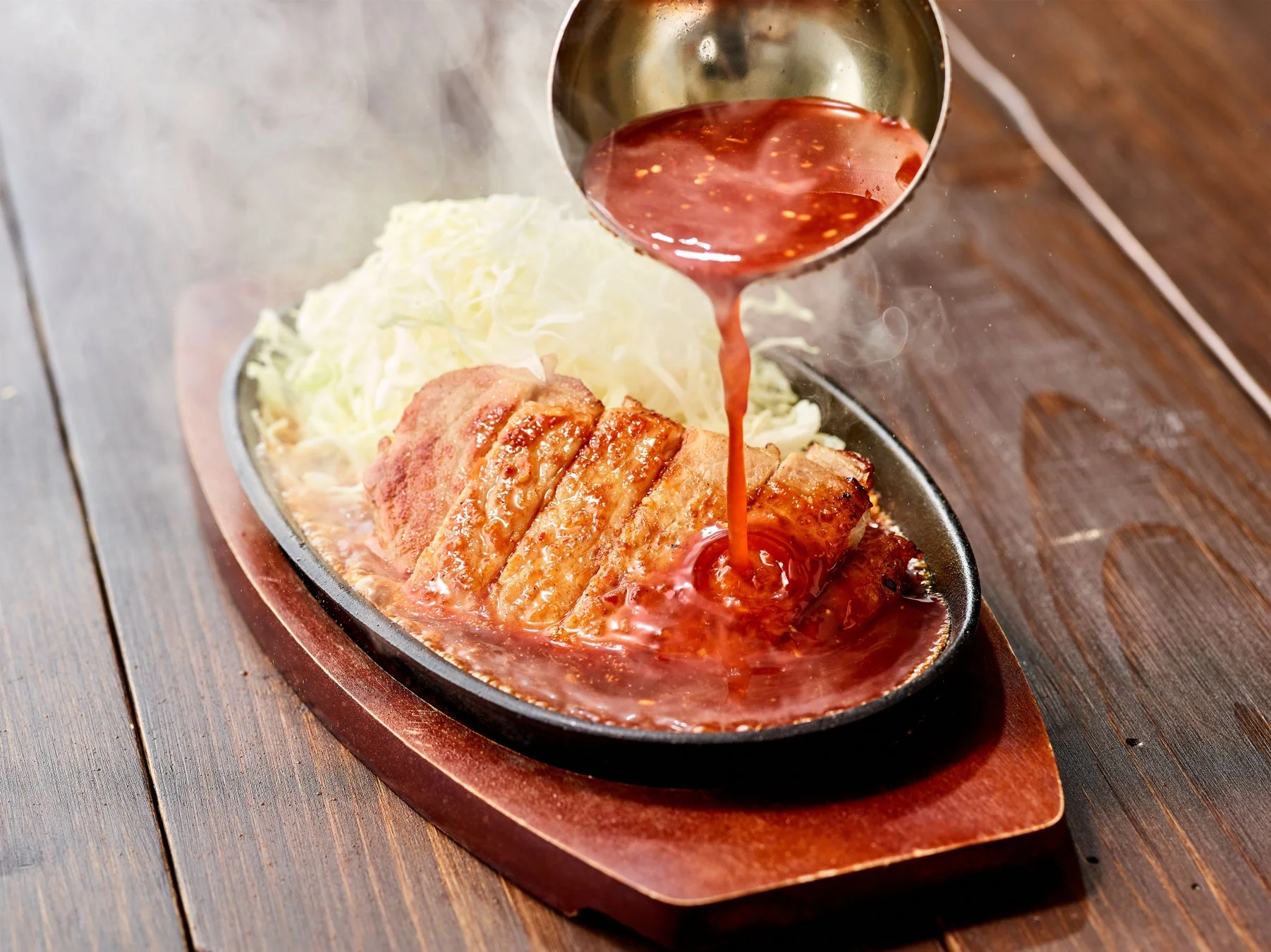 熱々鉄板で特製だれをジュワッとかける様子