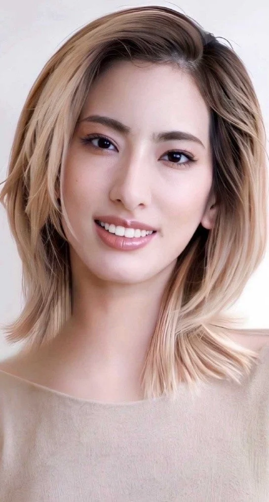 笑顔でカメラを見つめる、ミディアム丈のブロンドヘアの女性のクローズアップポートレートです。ナチュラルなメイクと優しい眼差しが特徴で、清潔感のある印象を与えます。
