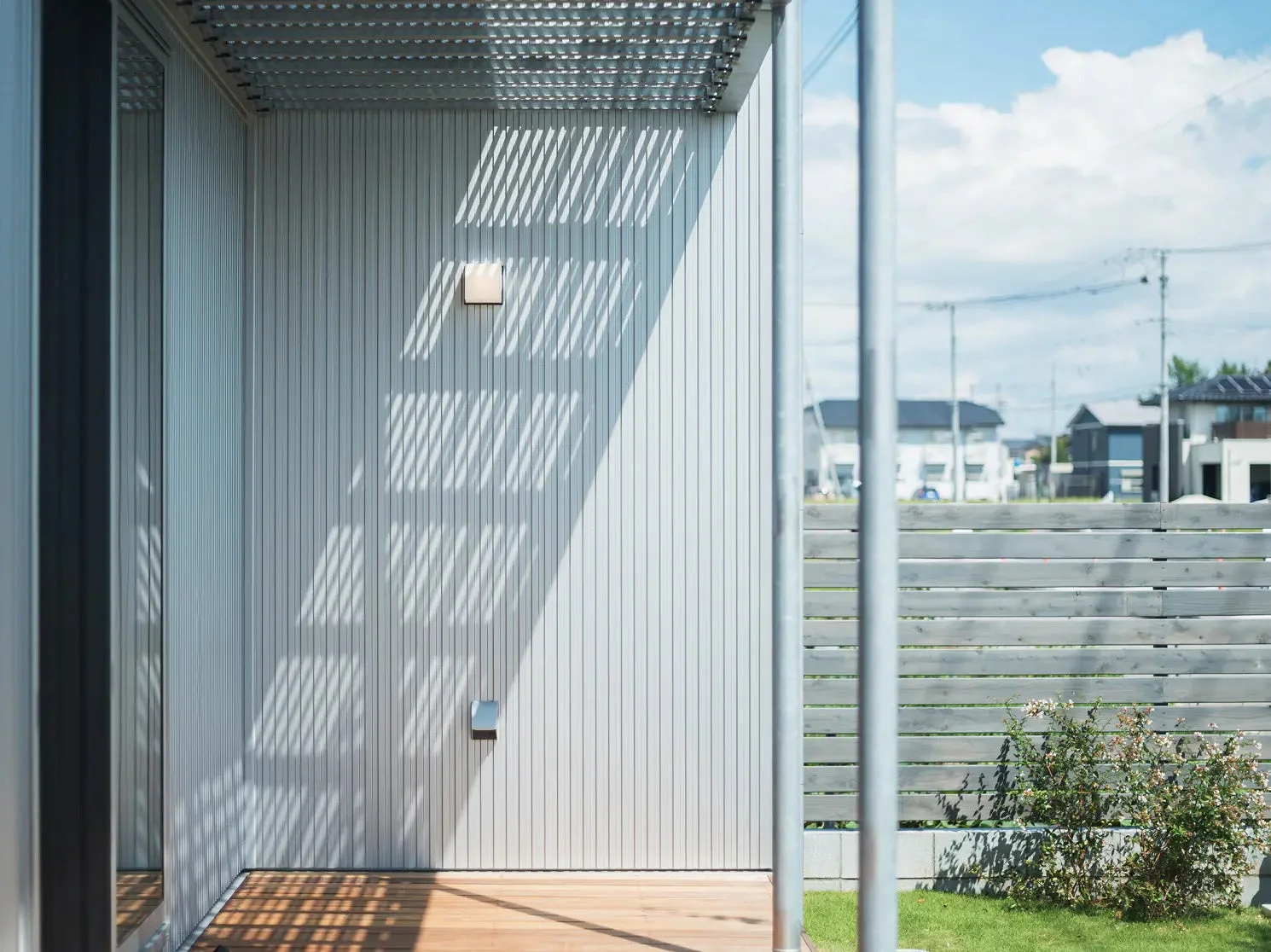 モダンな建物の外観とウッドデッキに日差しが作り出す影のパターン