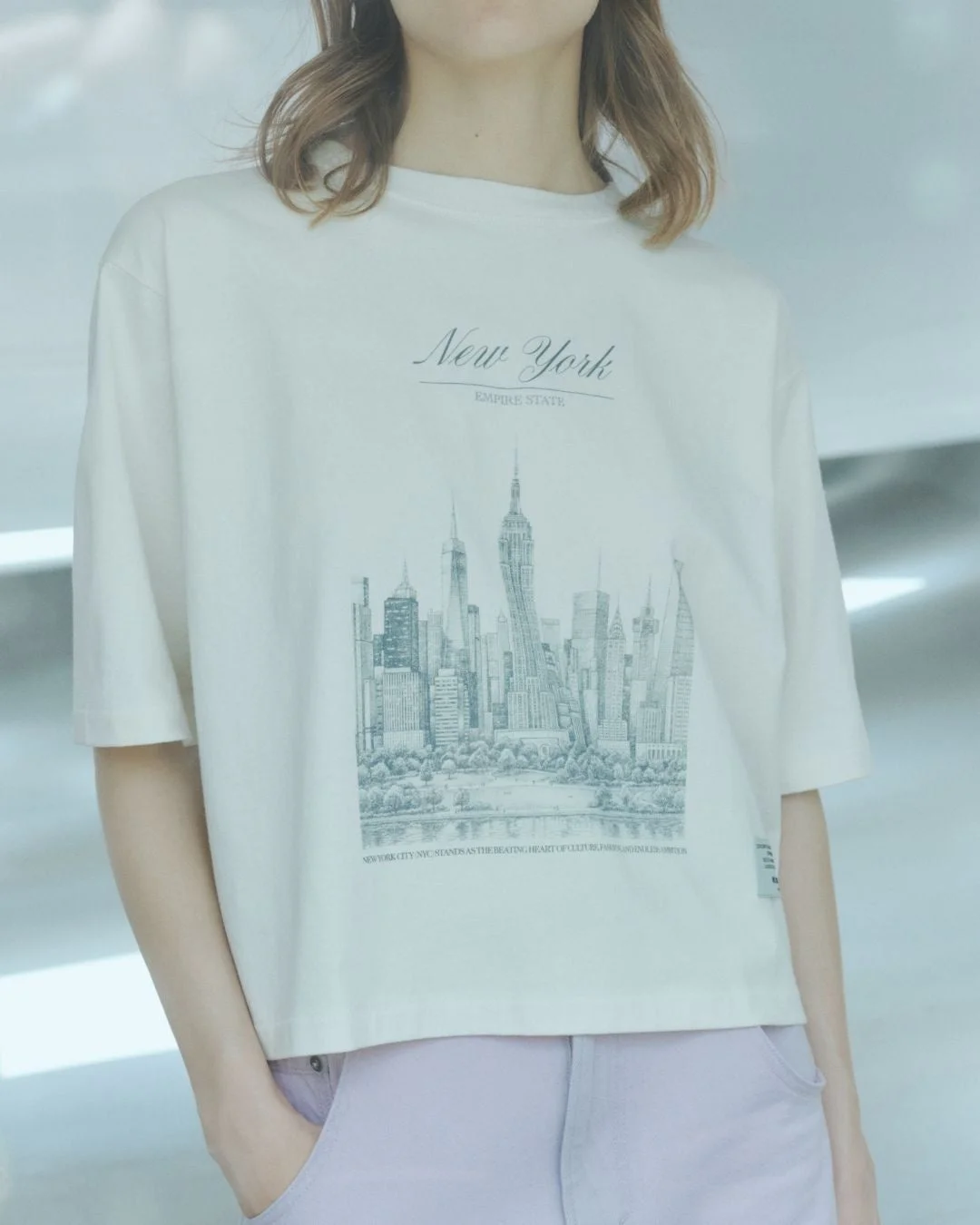 ニューヨークのスカイラインとテキストがデザインされた白いTシャツを着た女性