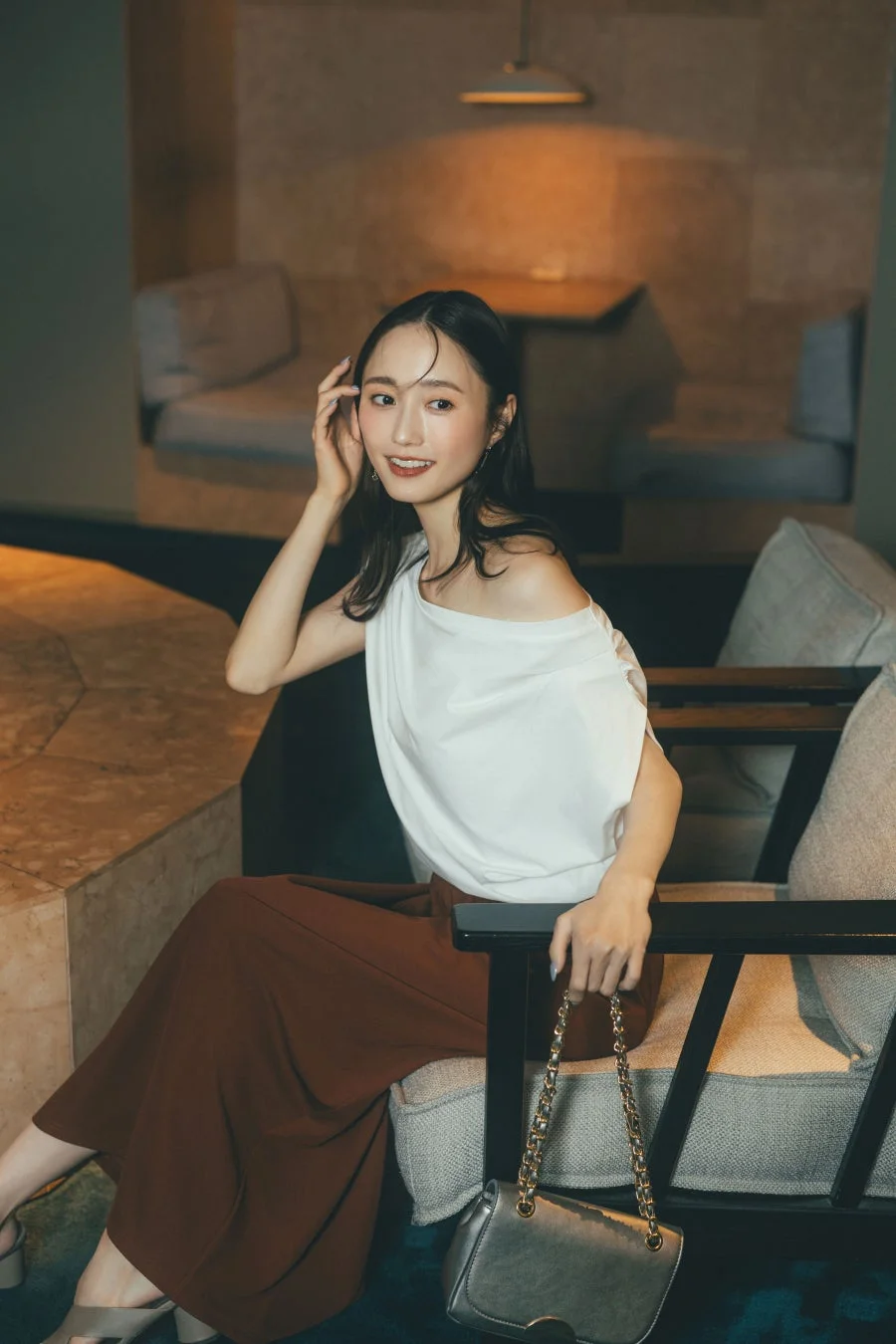 白いオフショルトップスとブラウンのワイドパンツの女性