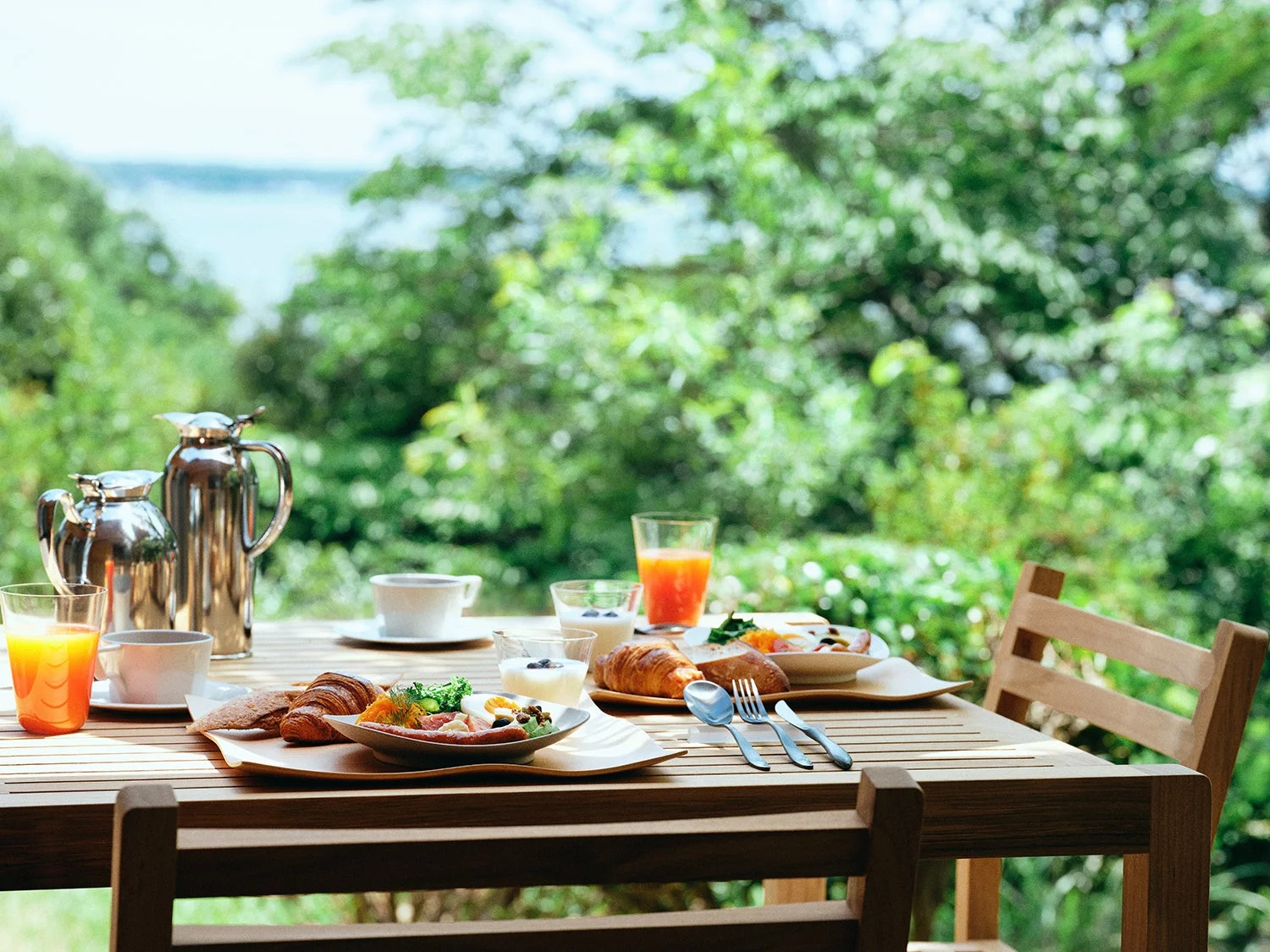 自然豊かな景色を望むテラスで、美味しそうな朝食が用意されたテーブルの様子。