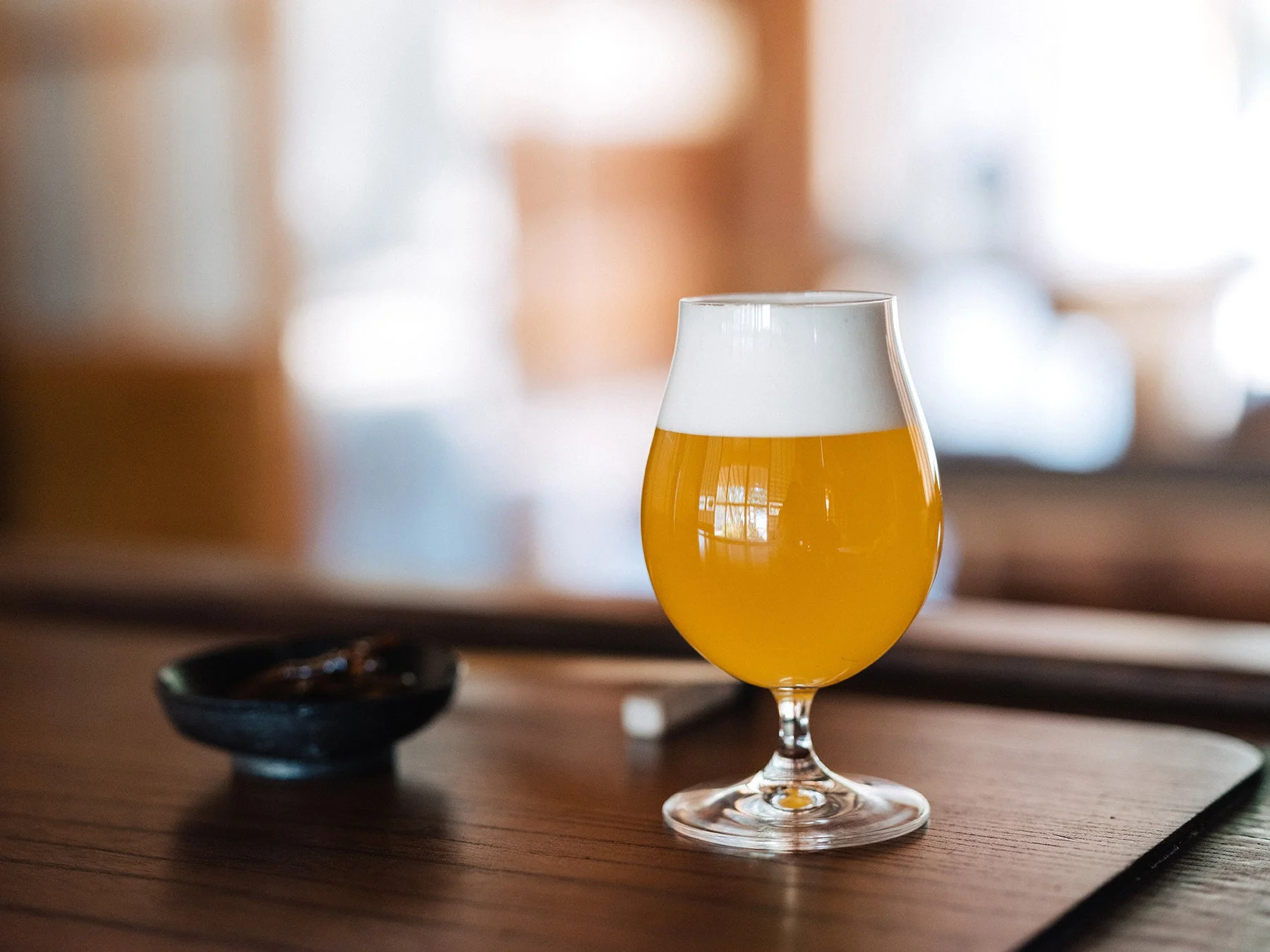 木のテーブルに置かれた、琥珀色のビールが入ったグラス
