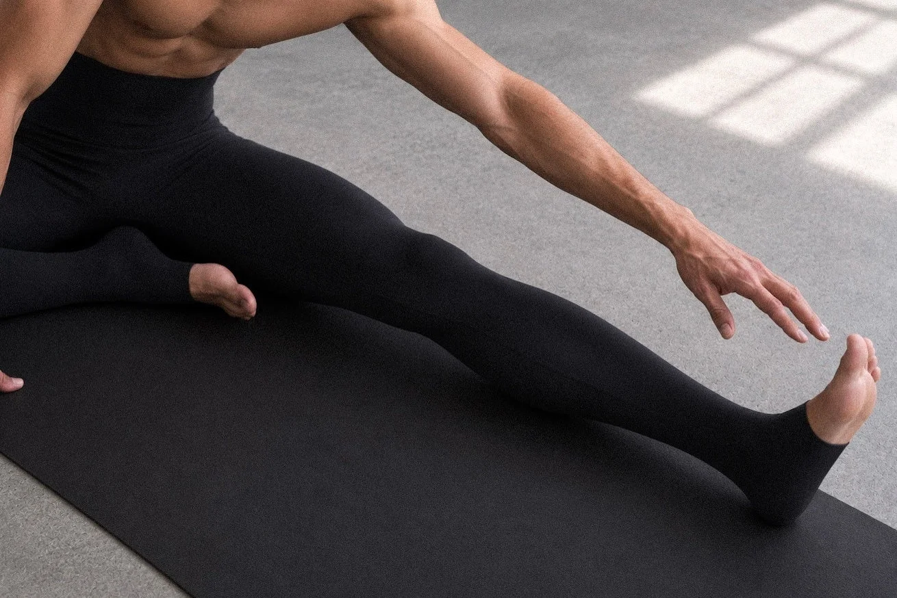ヨガマットでストレッチする男性