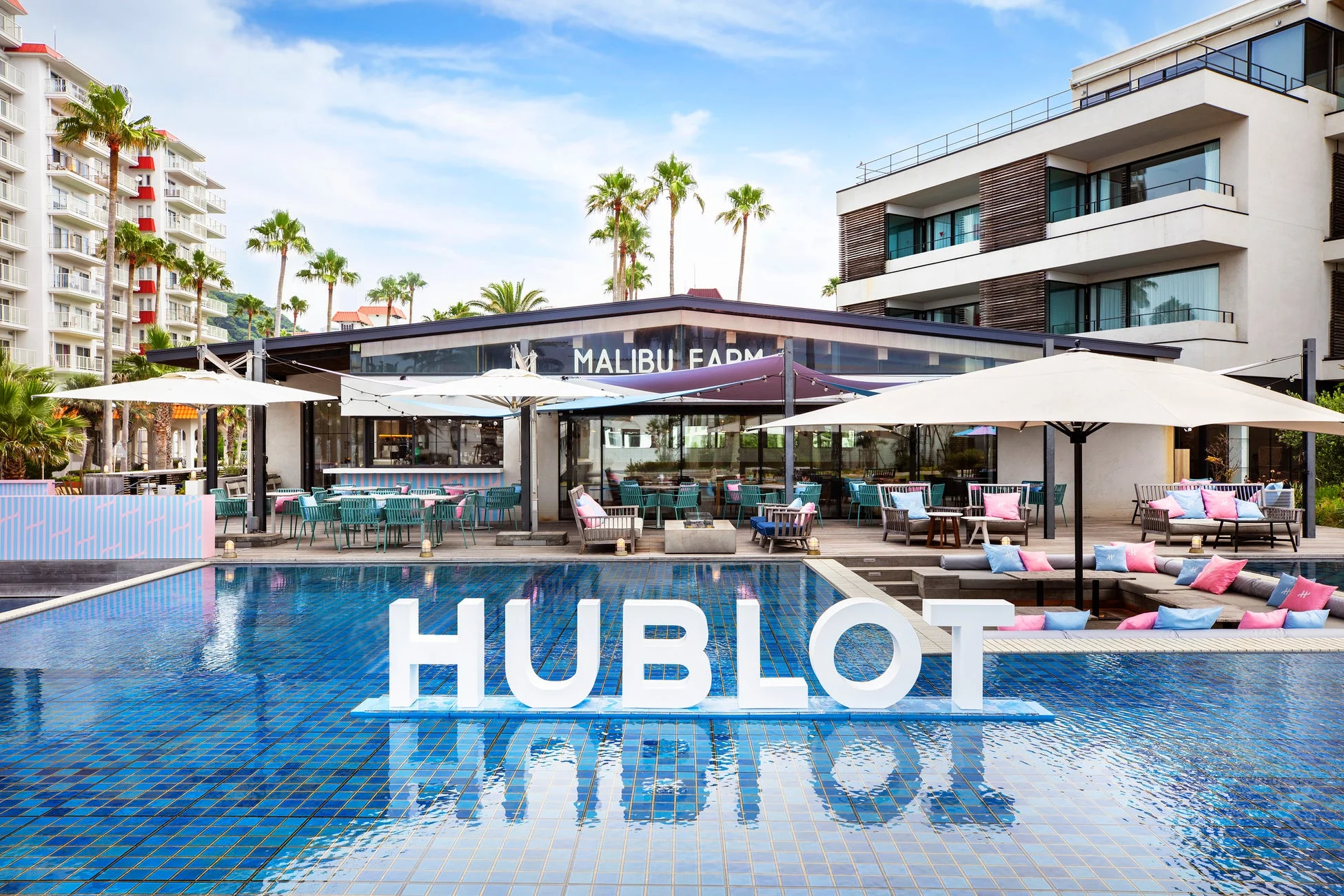 プールサイドに「HUBLOT」の文字が浮かぶ、リゾートホテルのような屋外空間