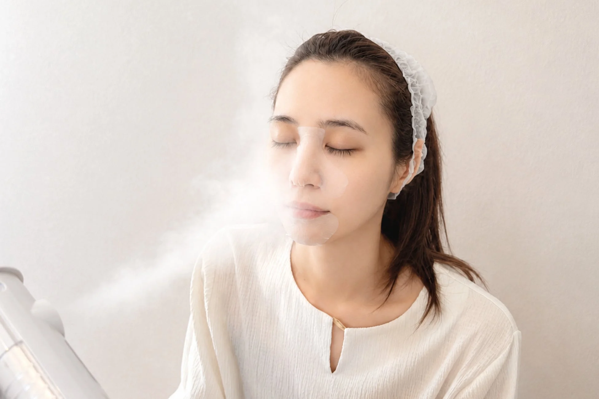 目を閉じてリラックスした様子の女性が、顔にスチーマーを当ててスキンケアをしている画像