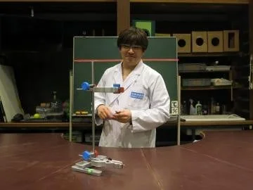白衣を着た男性が実験器具のテーブルの前に立つ