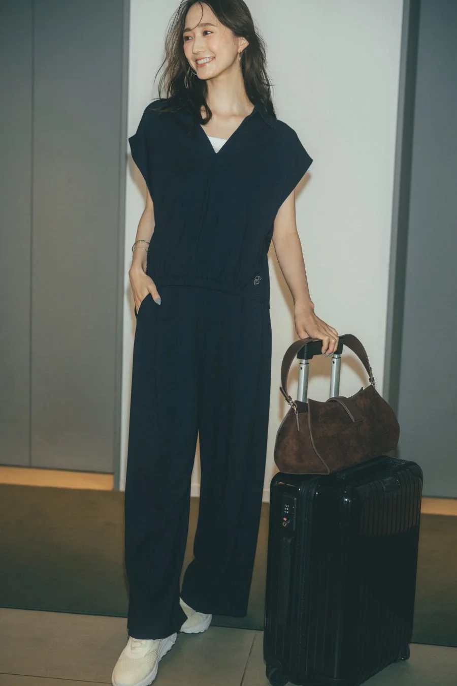 ネイビーのカジュアルセットアップを着た女性とスーツケース