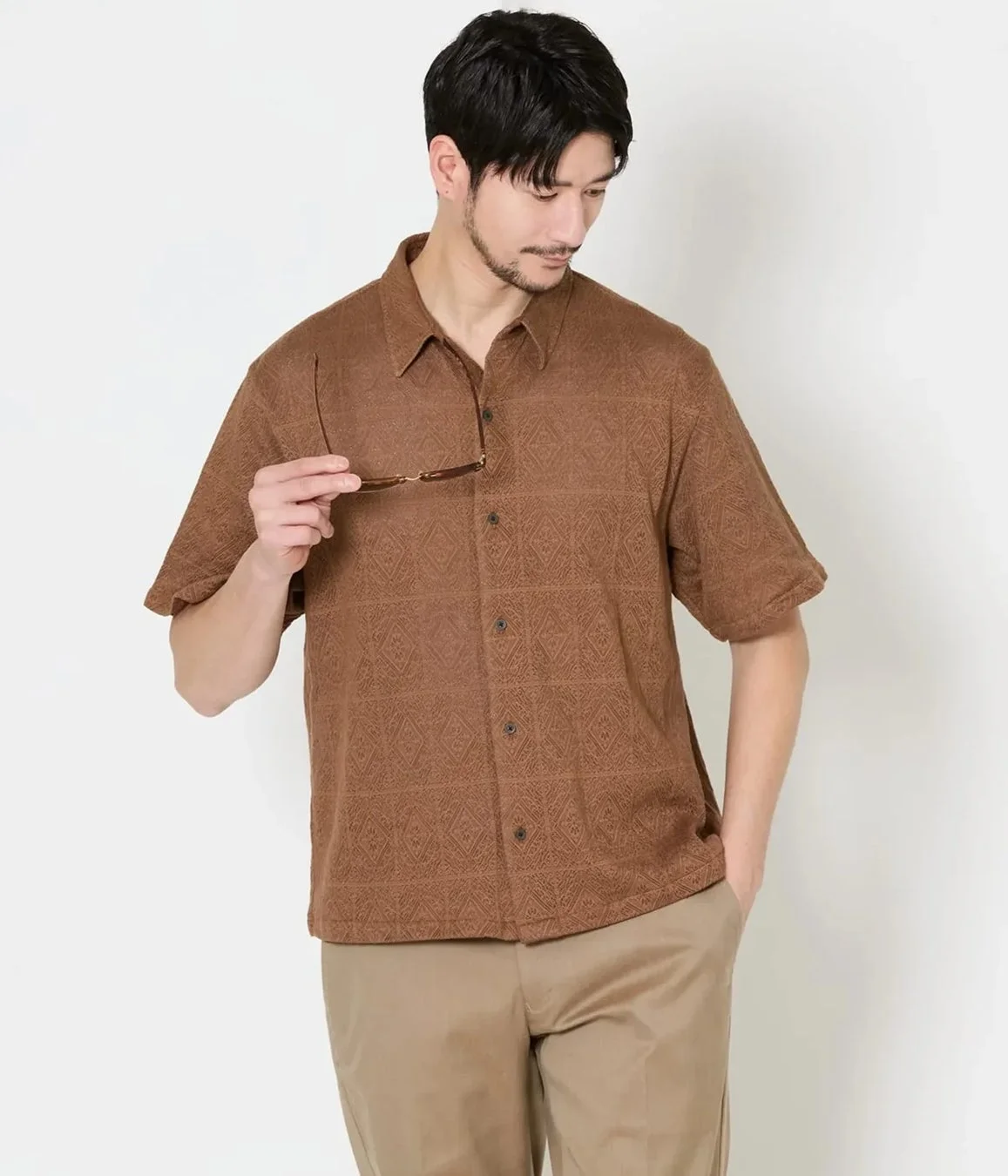 茶色の柄入り半袖シャツとベージュのチノパンを着用した男性