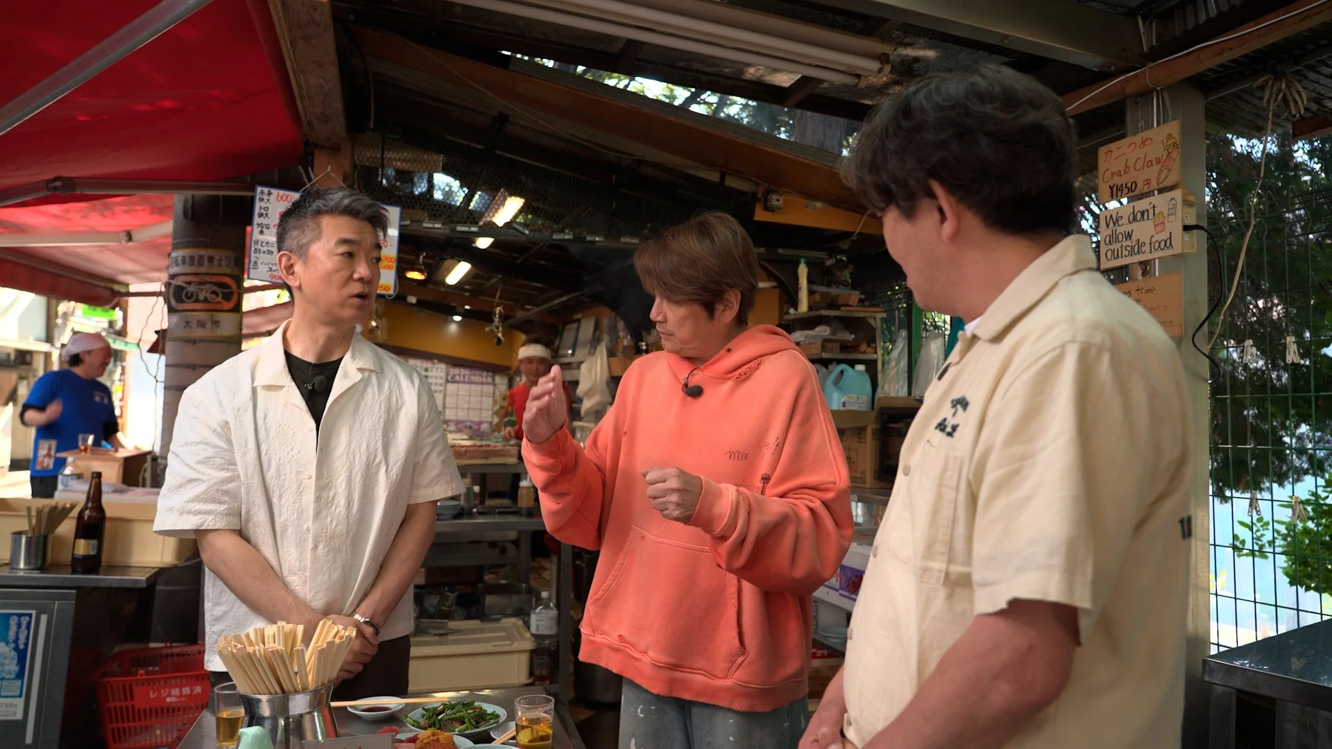 屋外の立ち飲み屋で談笑する3人