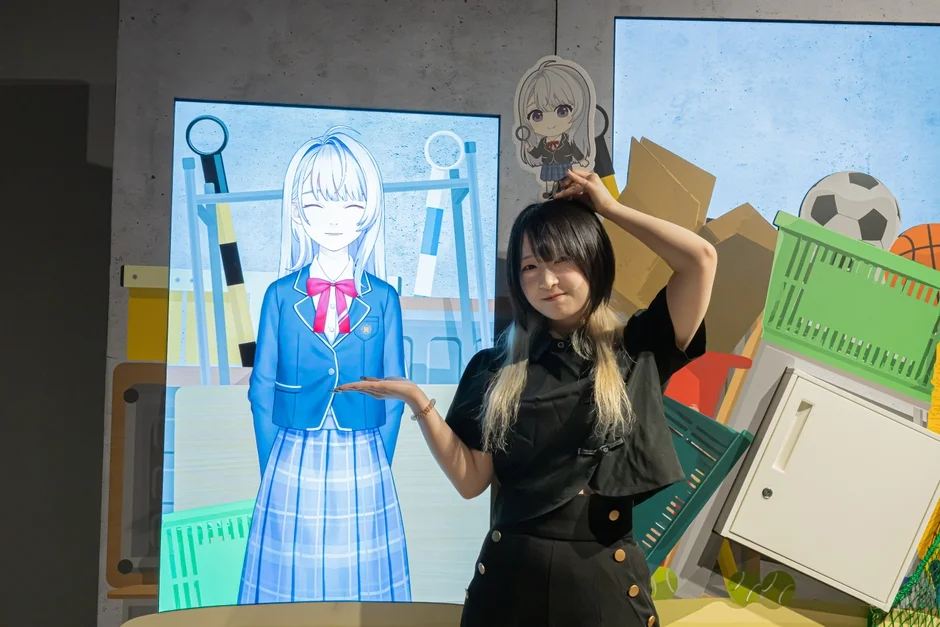 アニメキャラクターが映し出されたディスプレイの前に立つ和久野愛佳さん