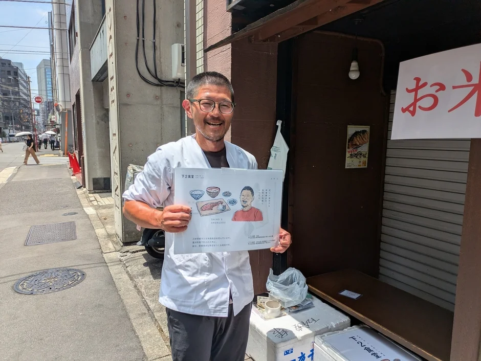 下2食堂店主の男性が看板を持つ様子