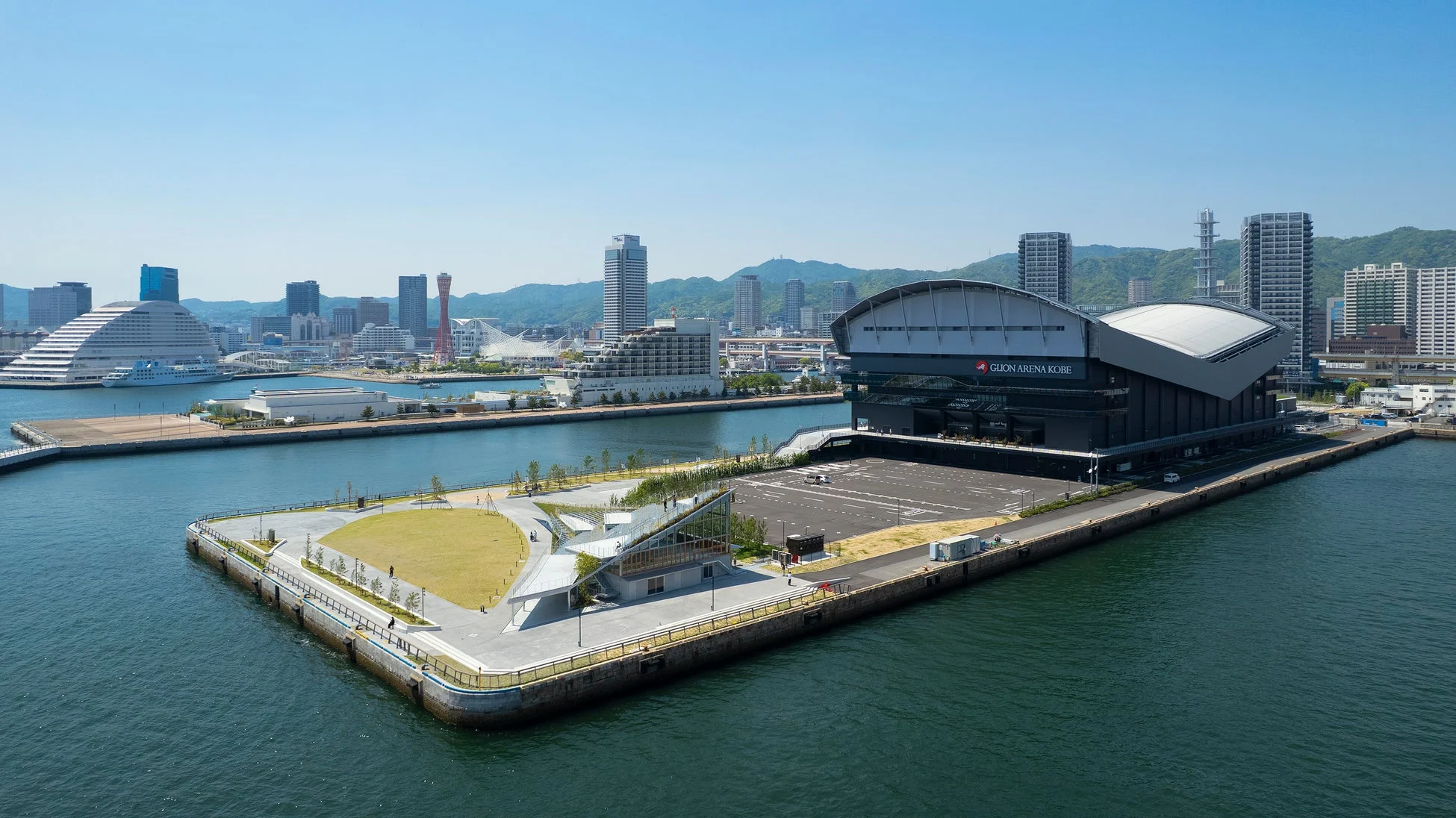 神戸のウォーターフロントに位置するGLION ARENA KOBEと周辺の公園、そして神戸の街並み