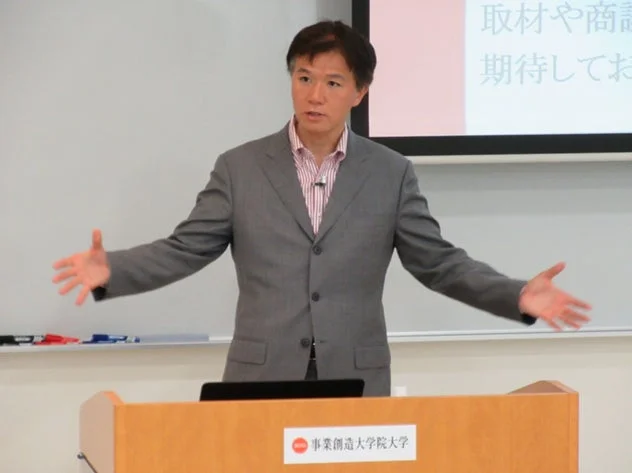 スーツ姿の男性が壇上で講演している様子