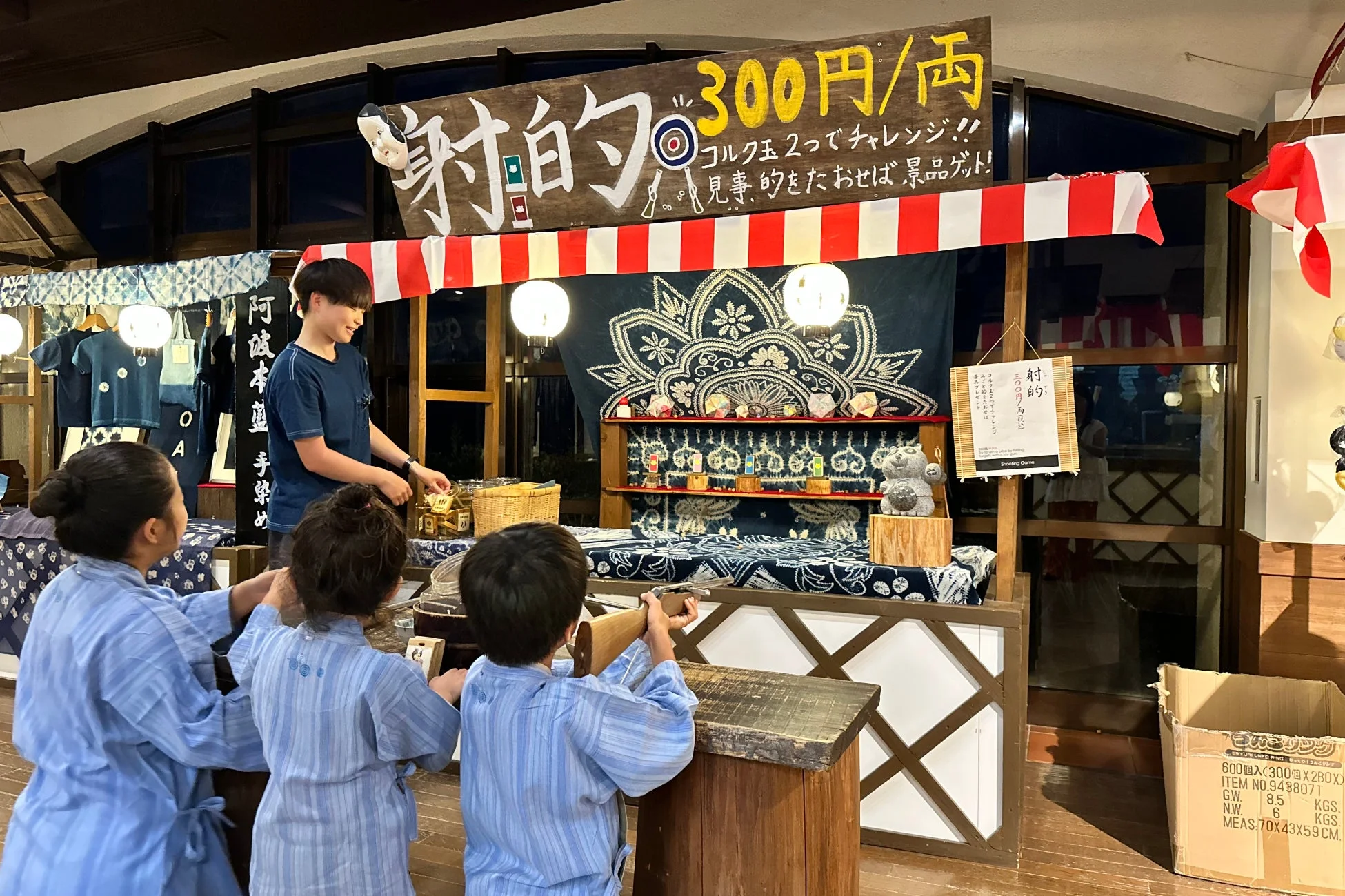 浴衣のような装いの子供たちが射的ゲームを楽しむ様子