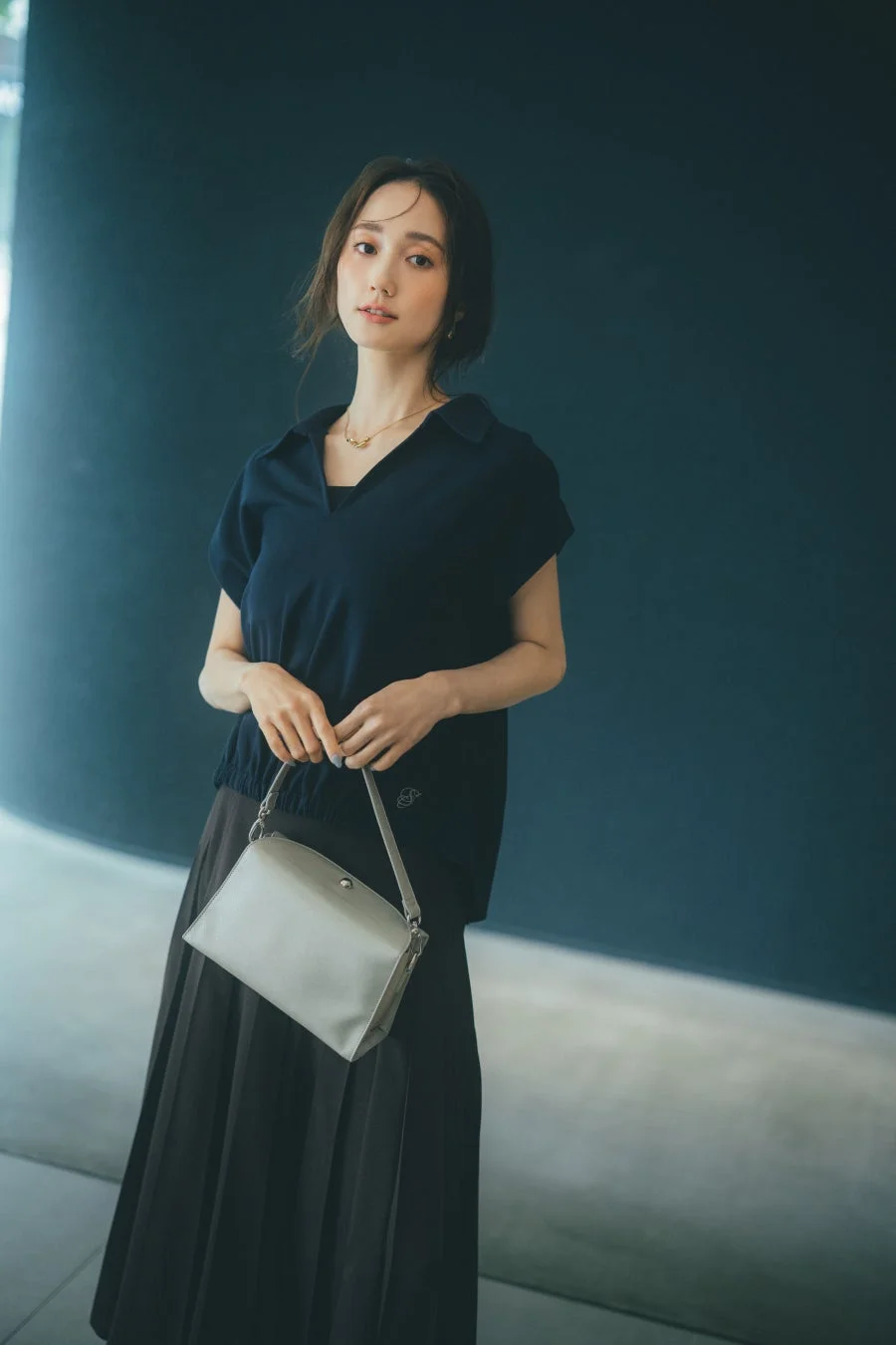 紺色のトップスとプリーツスカートを着用した女性