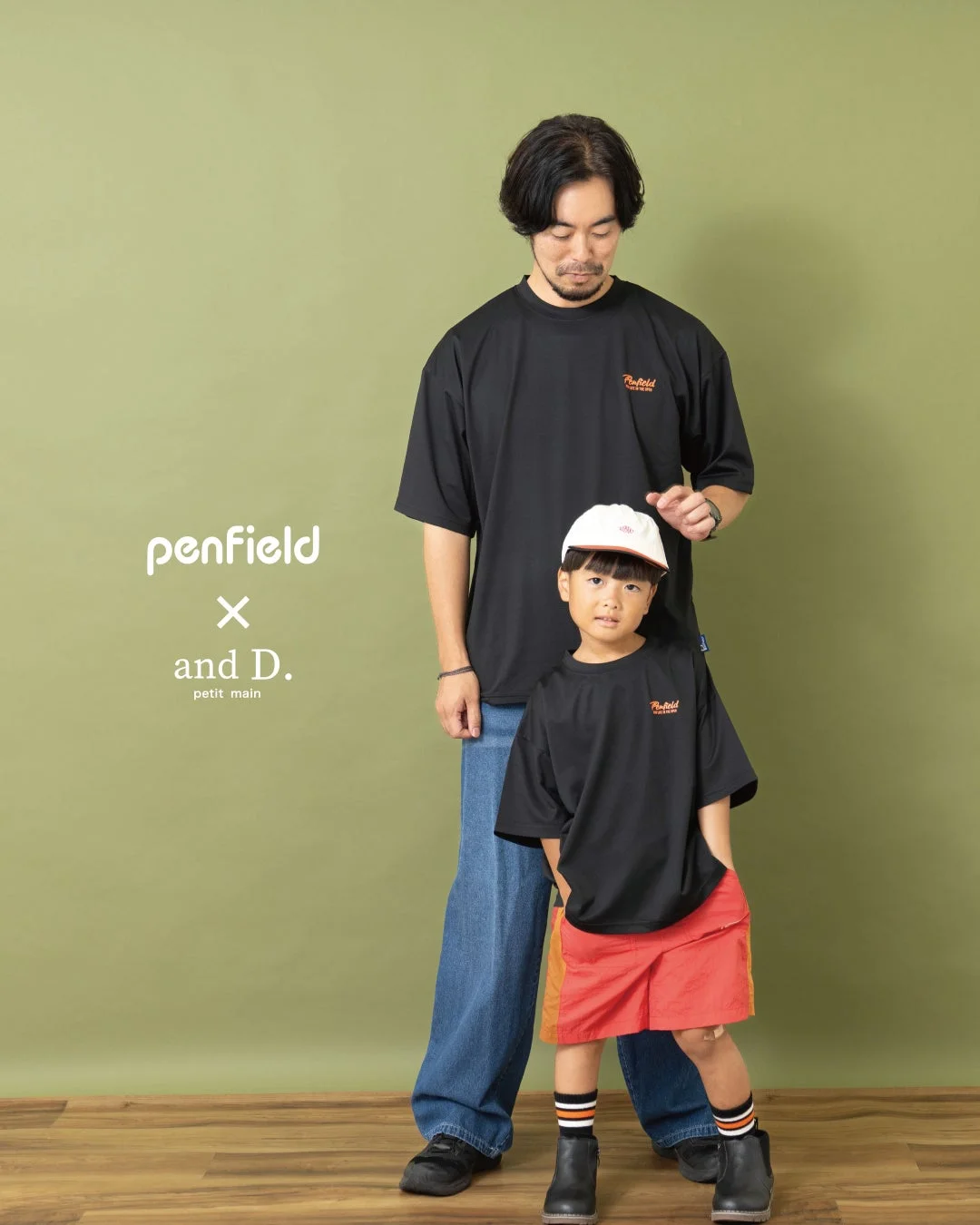 緑色の背景をバックに、黒いTシャツでリンクコーデをした親子