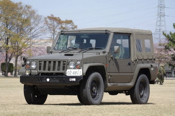 草地に駐車しているカーキ色の自衛隊の軍用車両