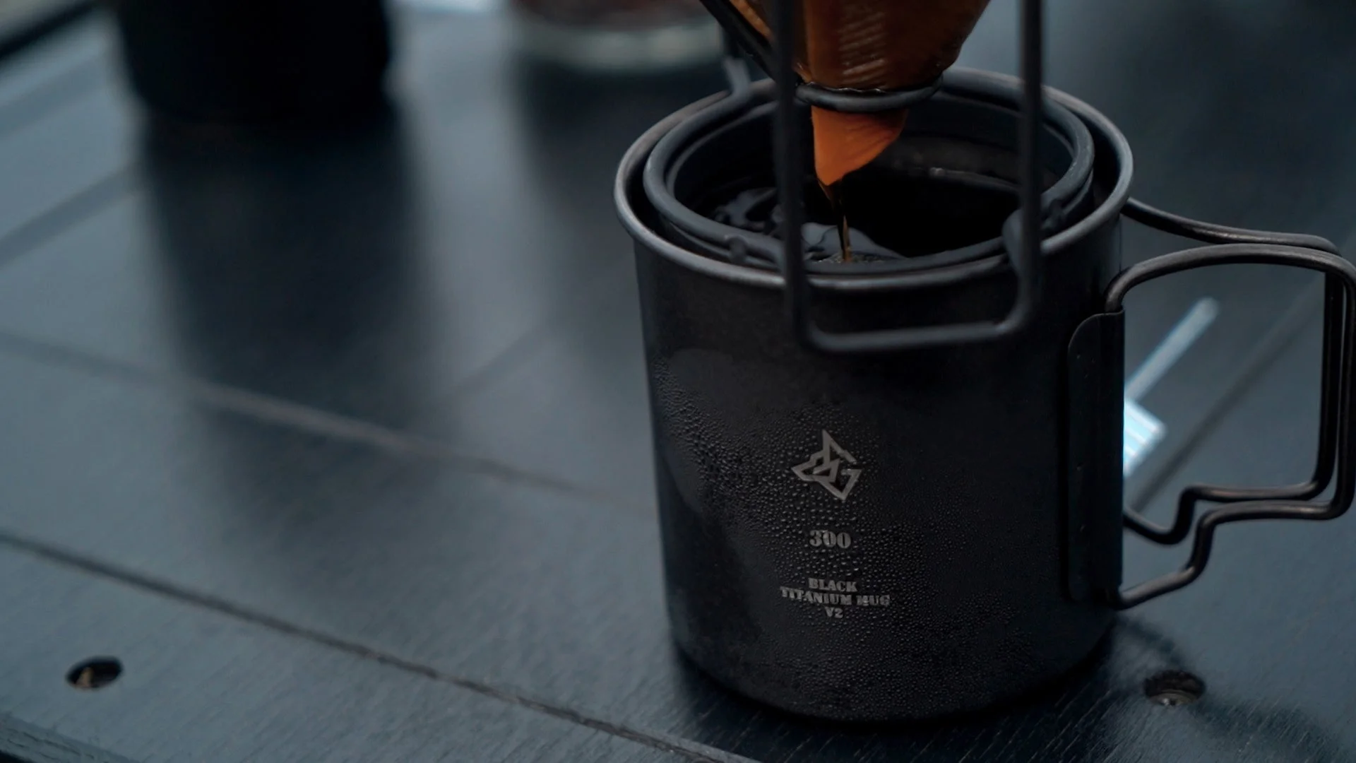 黒いチタン製マグカップにコーヒーが注がれている様子