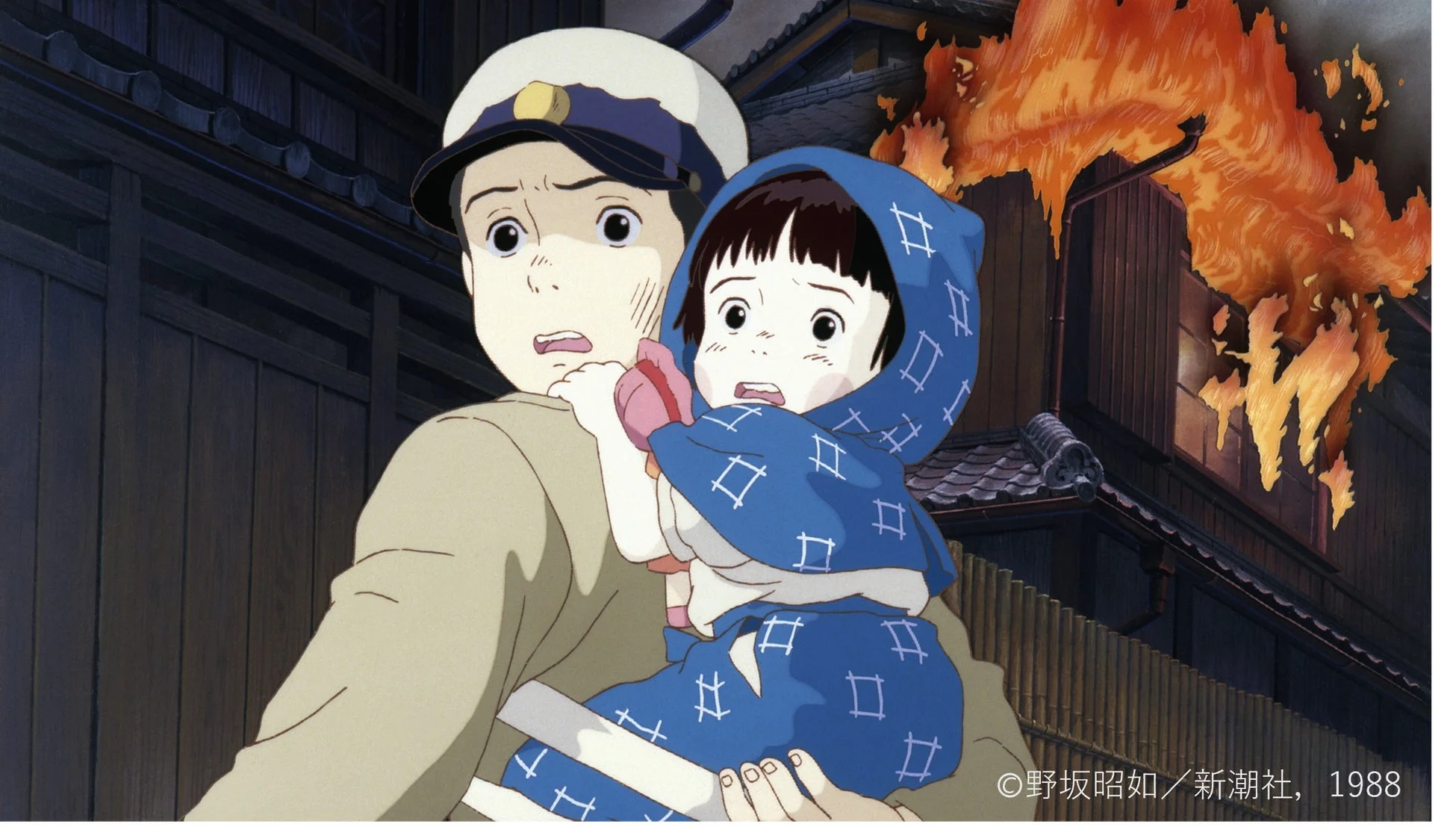 火災に見舞われた家屋を背景に、恐怖におののく兄と妹が描かれています。戦争の悲劇と避難の様子を伝える、アニメ映画「火垂るの墓」の一場面です。