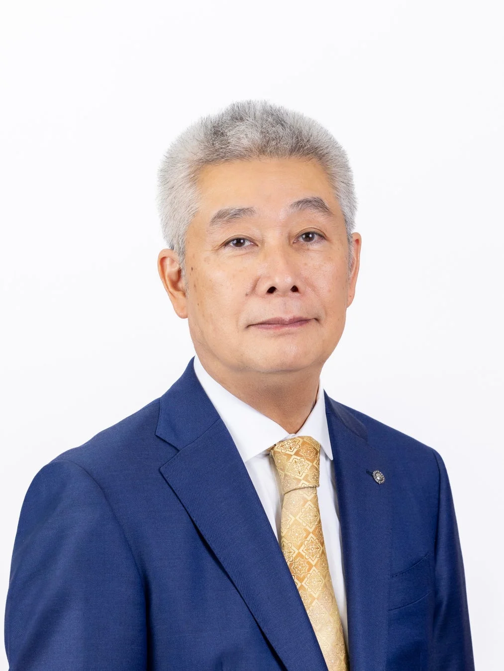 青いスーツと金色のネクタイを着用した白髪の東洋人男性のポートレートです。男性はカメラをまっすぐ見ており、表情は真剣です。背景はシンプルな白です。