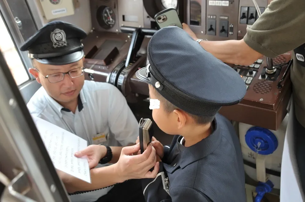 電車の運転席で制服を着た男の子が運転体験をしている様子