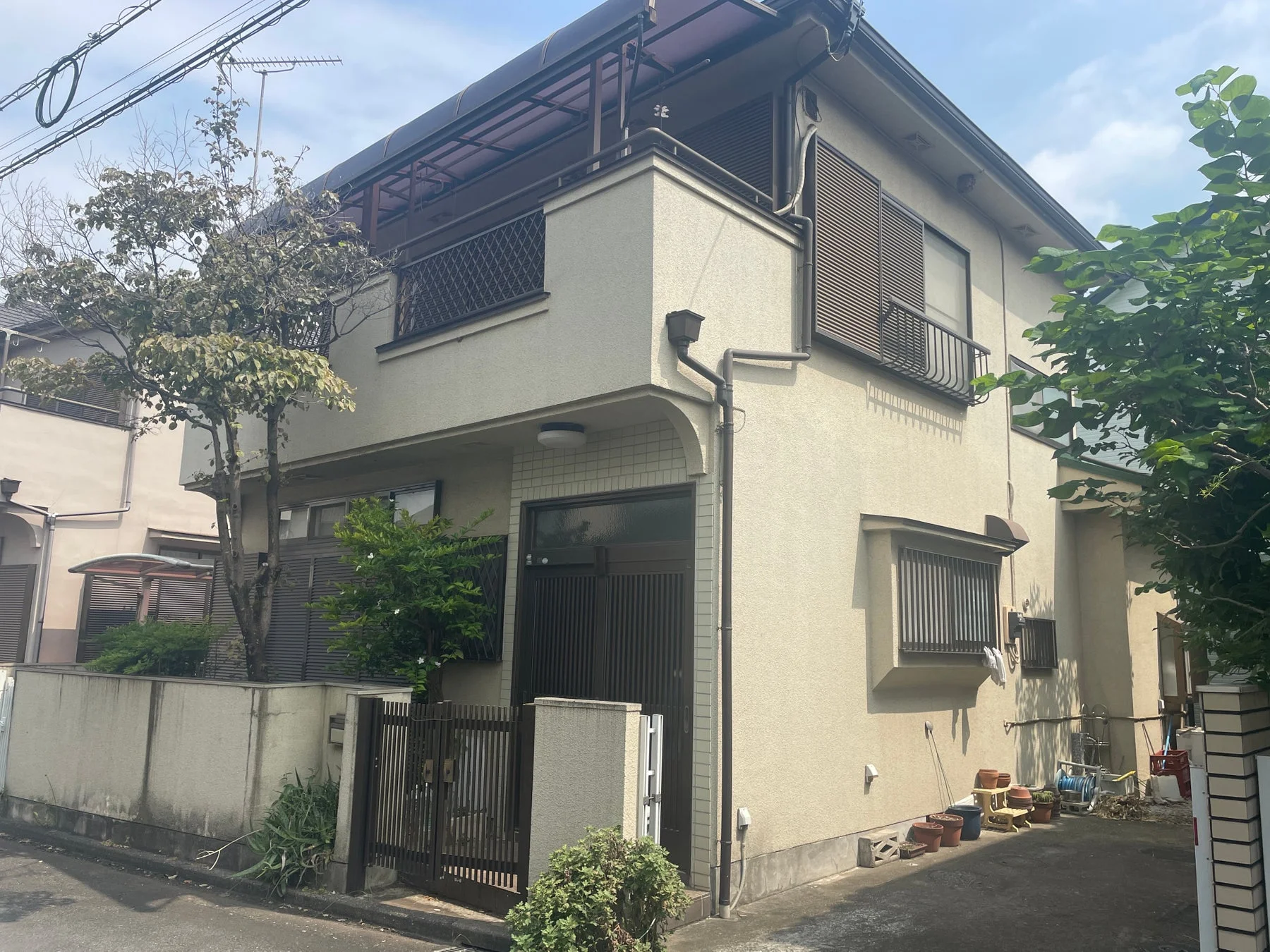 青空の下に建つベージュ色の2階建て住宅