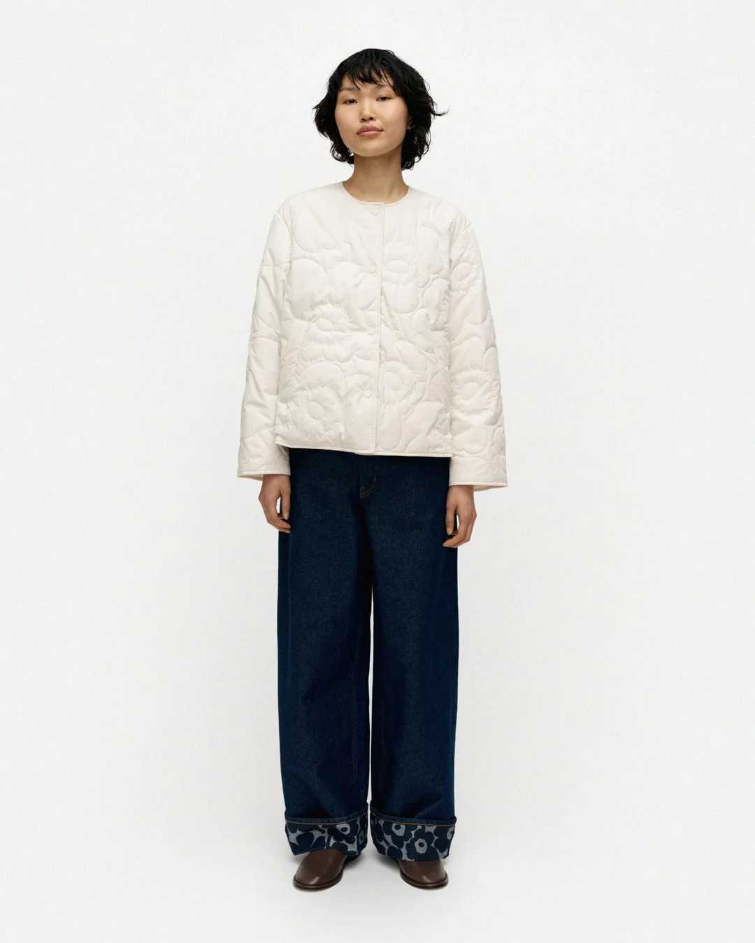 オフホワイトのキルティングジャケットとワイドデニムを着た女性