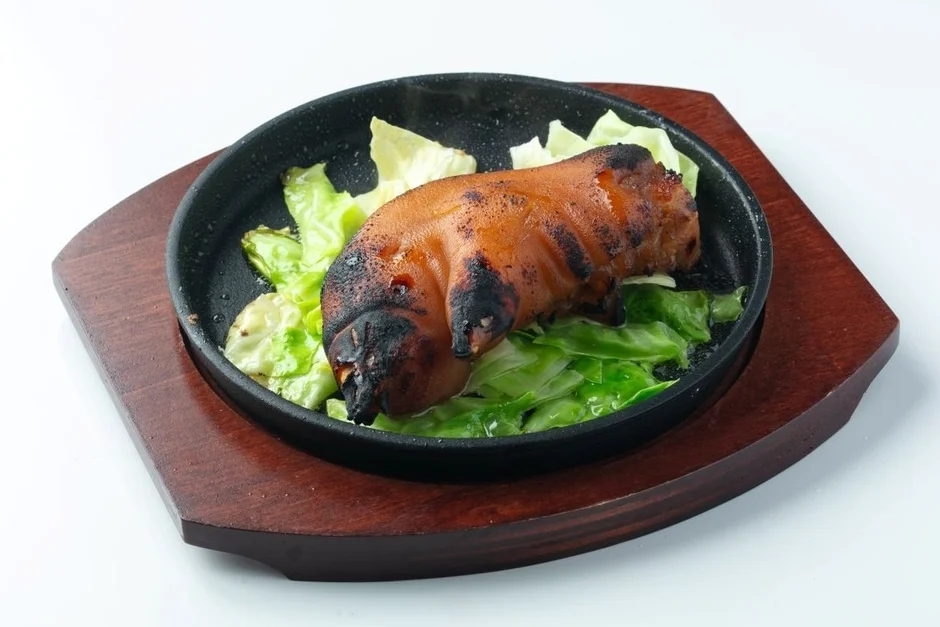 熱々の鉄板に盛り付けられた焼き豚足とキャベツ