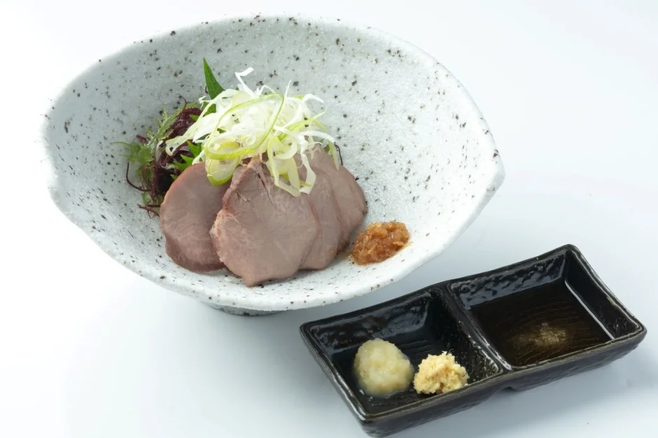 薄切り肉(牛タンまたは豚肉)が盛り付けられた和食の一品