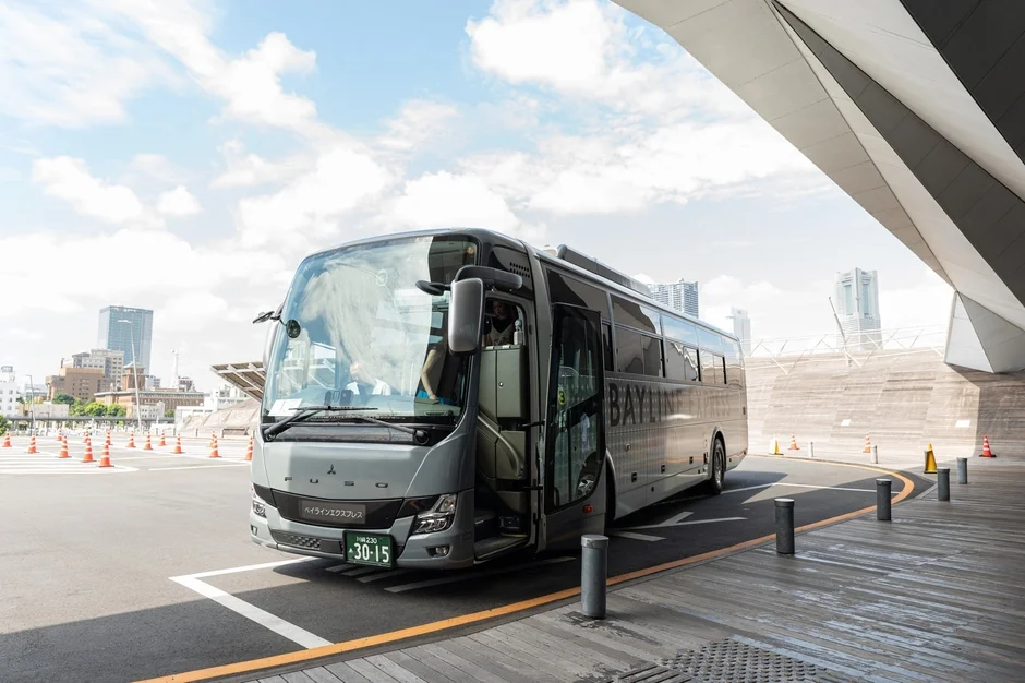 晴れた日に近代的な建物の前で停車しているグレーの観光バス