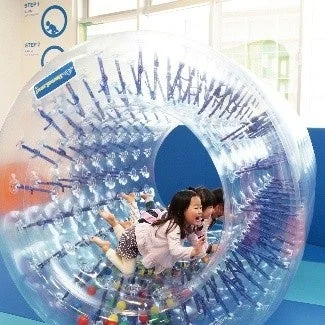 複数の子供たちが透明な巨大なエアランナーの中で楽しそうに遊んでいる