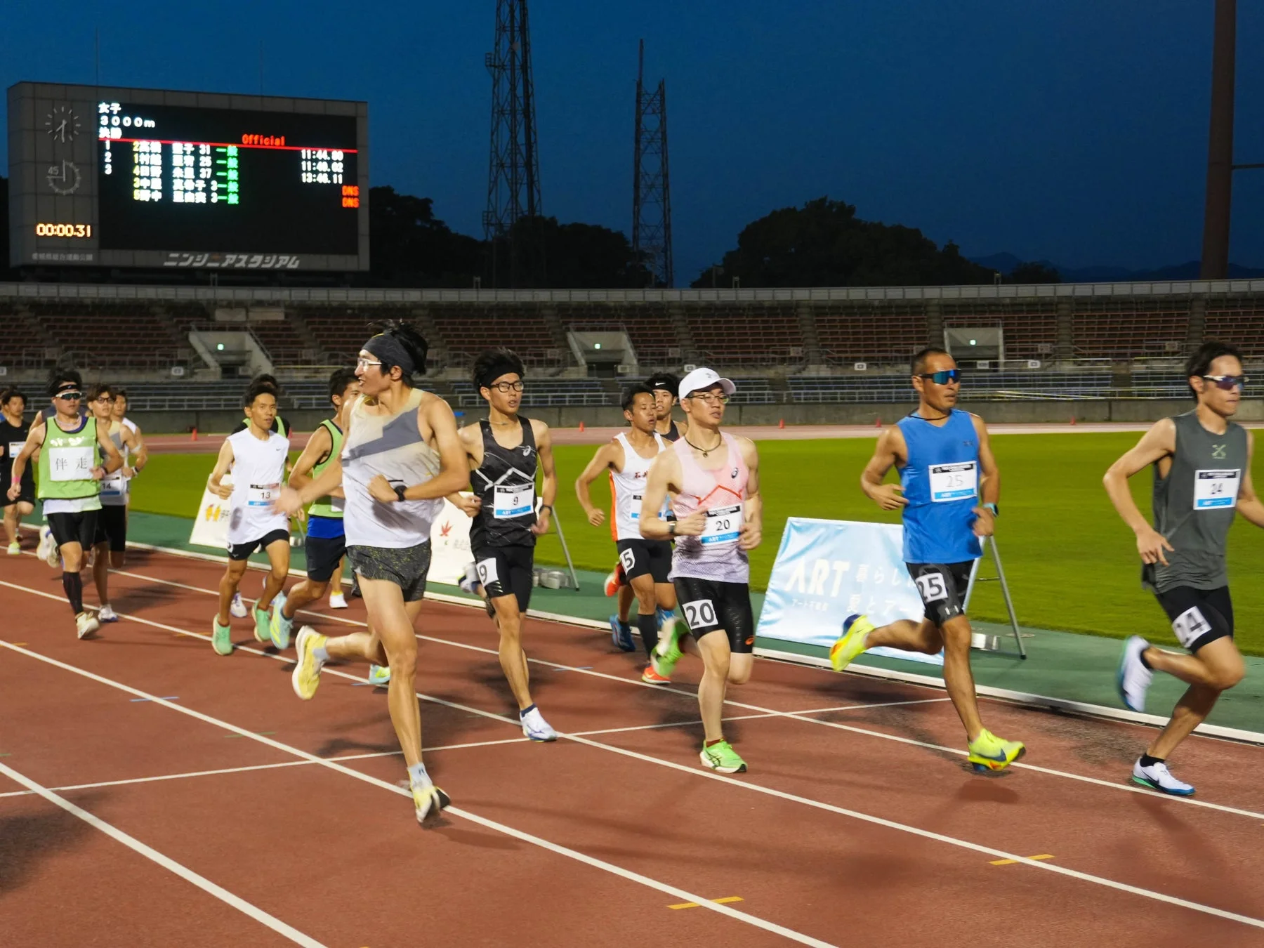 夜間の競技場でランナーが走る様子
