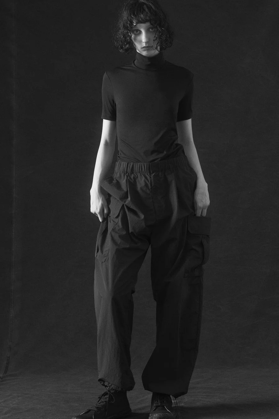 Monochrome full-body shot of a model in a turtleneck and cargo pants