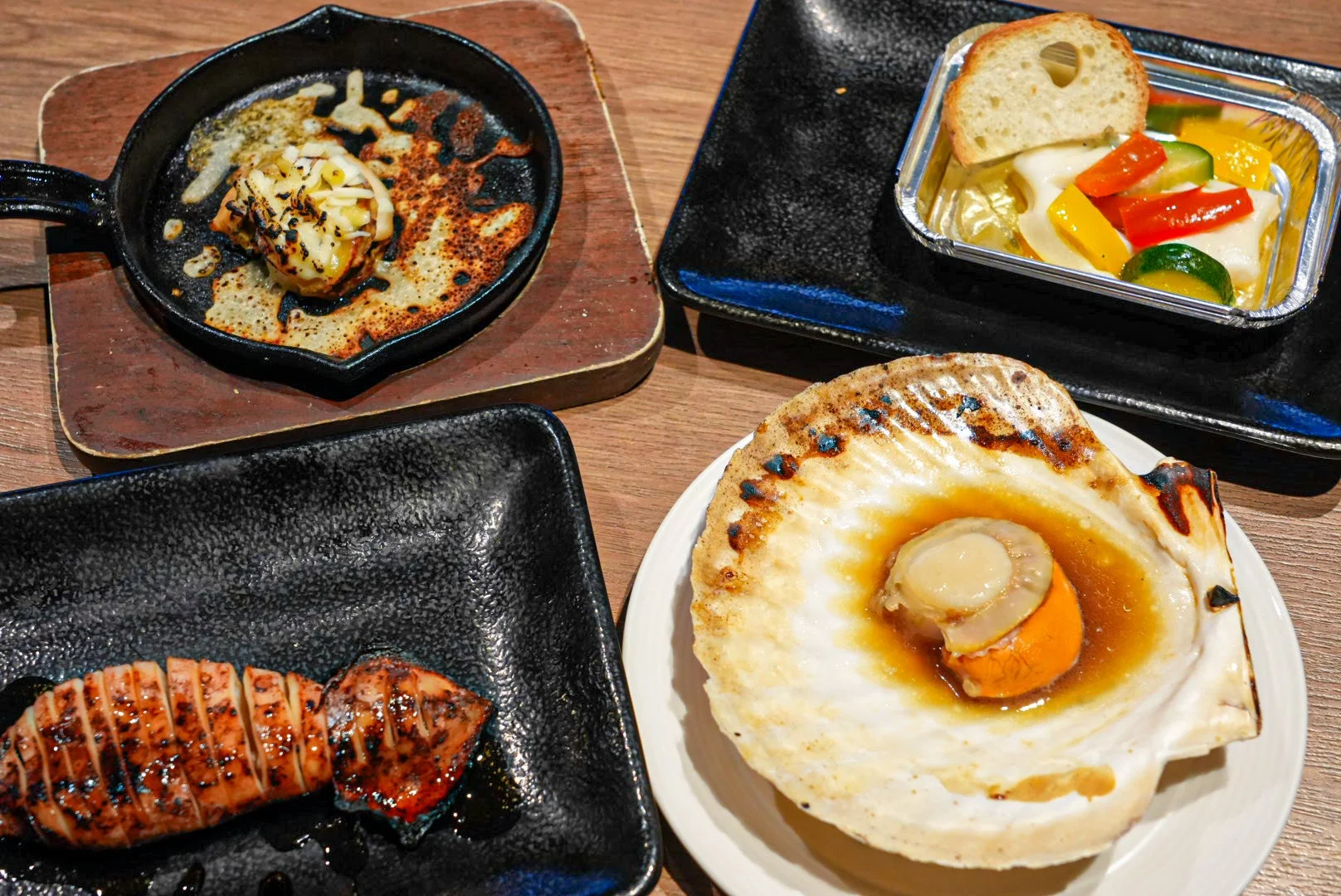 焼きイカ、ホタテの浜焼き、チーズ焼き、野菜のマリネなど、様々な海鮮料理と一品料理が並ぶ食卓の様子。温かい料理が食欲をそそります。