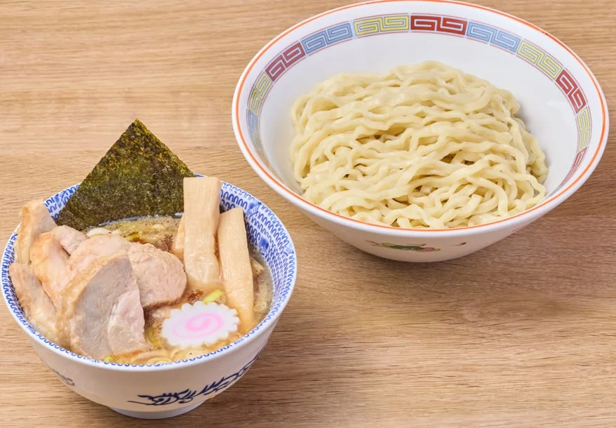チャーシュー、メンマ、のり、なるとが盛り付けられた濃厚なつけ汁と、別の器に盛られた太麺が特徴的な、食欲をそそる一品
