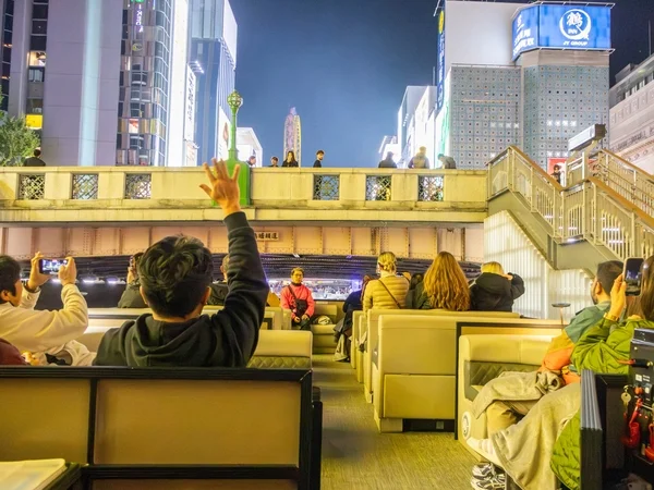 大阪の道頓堀で夜の川クルーズを楽しむ人々が写っています。船上から橋の上にいる人々に手を振る様子が見られ、ライトアップされた街並みが賑やかな雰囲気を醸し出しています。