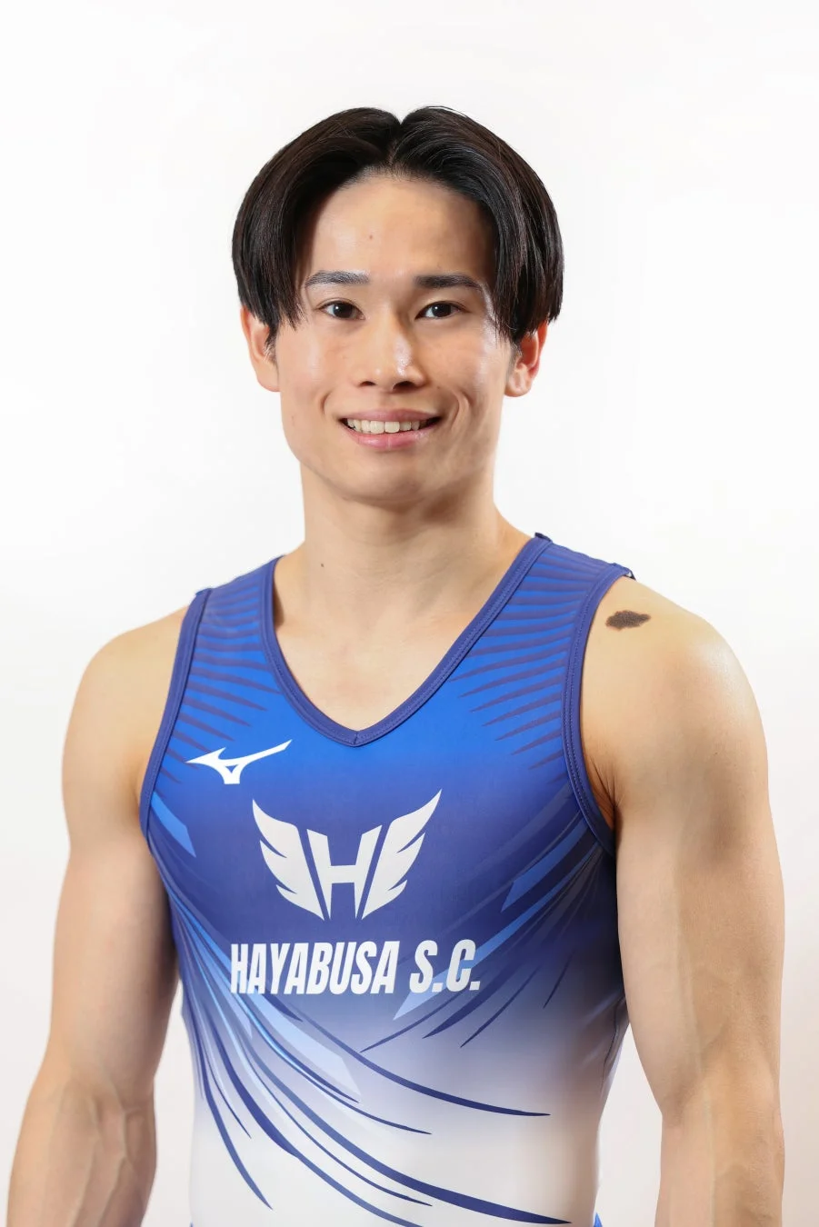 青と白の体操ユニフォームを着用し、笑顔でカメラを見つめる日本人男性アスリートのポートレート