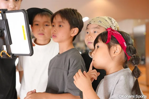 大人と一緒にタブレットの画面を見つめる子供たち