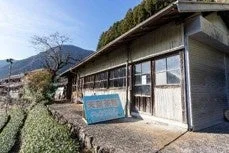 晴れた日に山間部にある古い木造の建物と茶畑