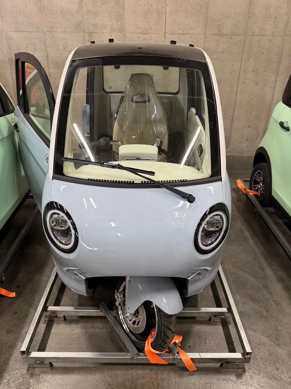 輸送中の明るい水色の三輪マイクロカー