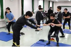 室内で複数の若者が抵抗バンドを使ったトレーニングを行っています。