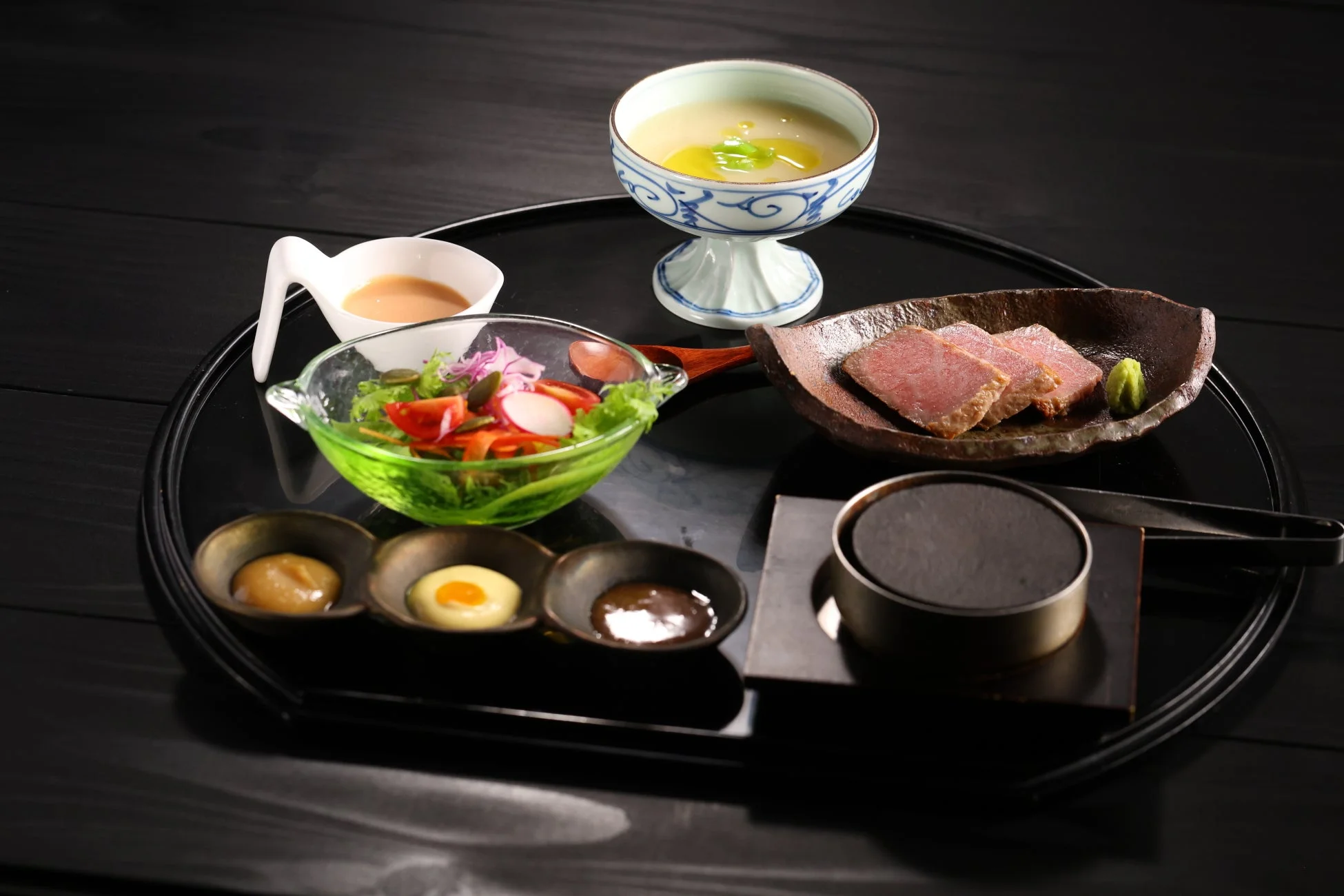 黒いお盆に美しく盛り付けられた和風のコース料理