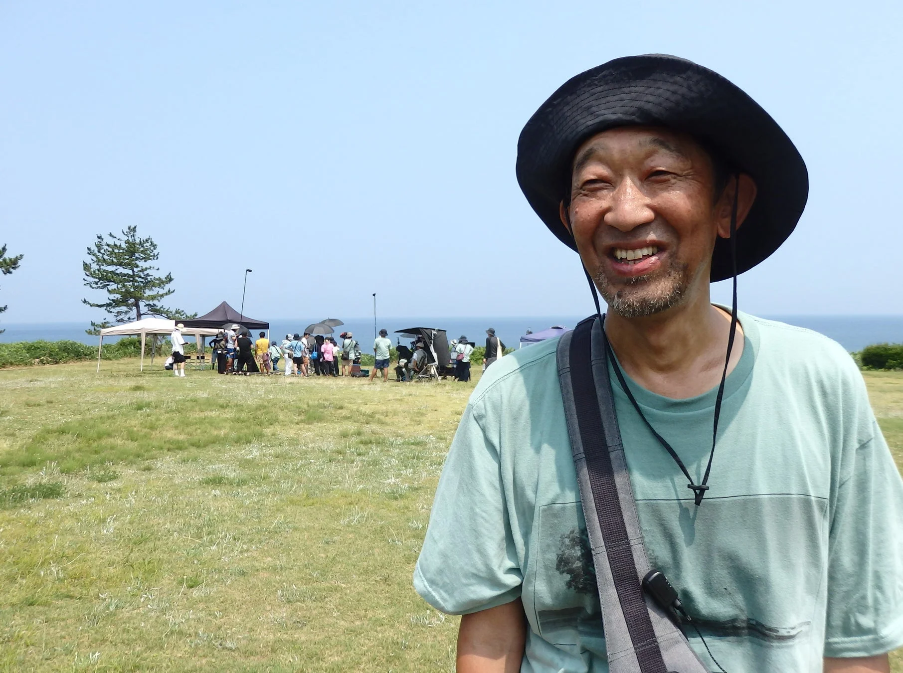 海を背景に笑顔で話す男性と人々