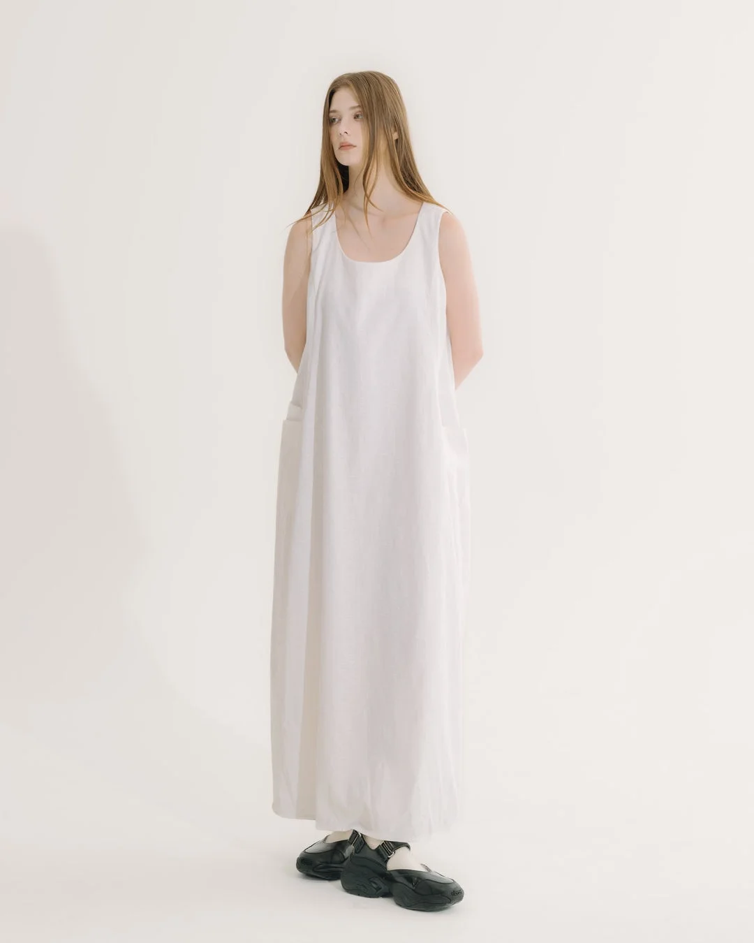 白いノースリーブのマキシ丈ワンピースを着用した女性